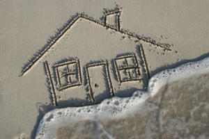 House drawn in sand, swept away by tide